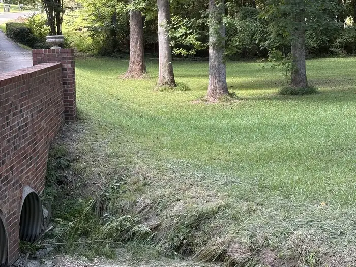 The same creek bank after Gaskins Lawn Care cut the reeds back to the pipe