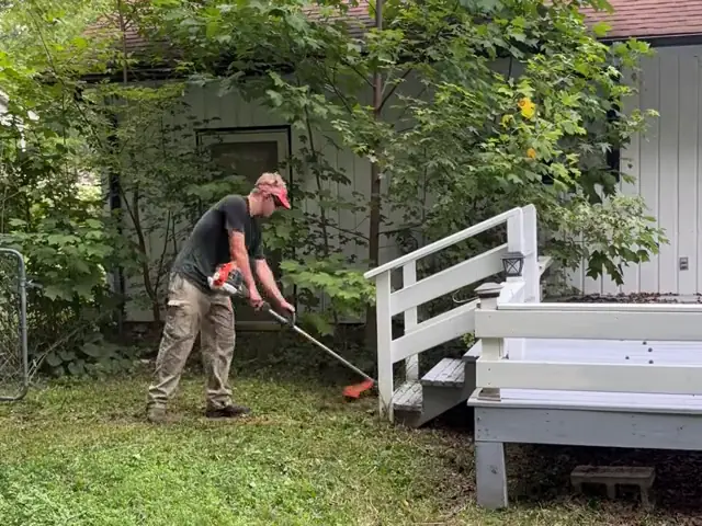 Weed eating around the steps of a back deck