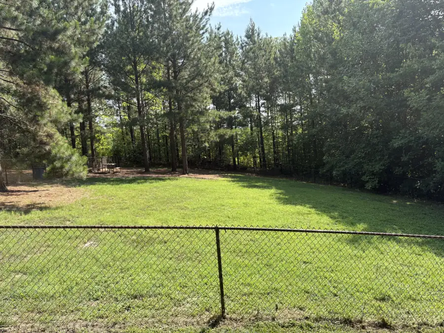 A back yard in Randolph County, NC with a long chain link fence line running along a treeline